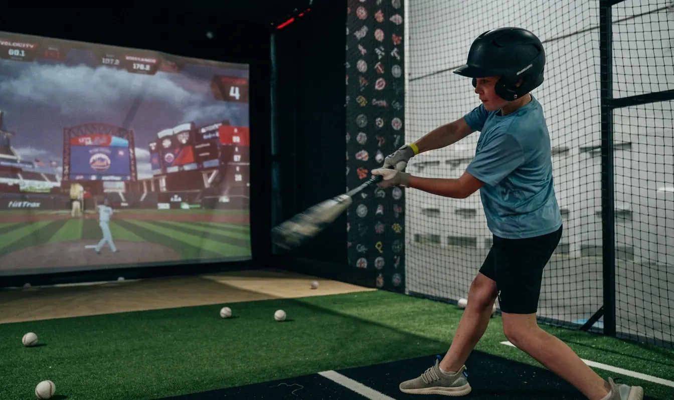 A young player swinging in front of the ProBatter screen